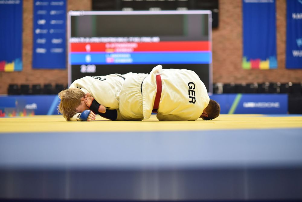German judo athlete bowing on the mat during a competition at an indoor sports arena.