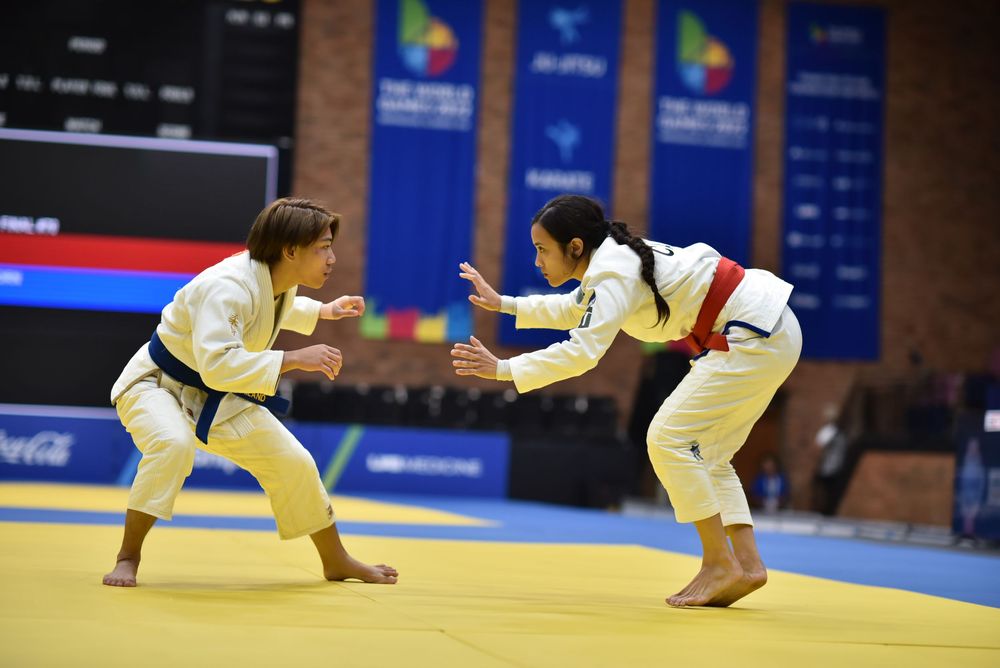 Two female judo athletes compete on a mat during an international judo championship tournament match.
