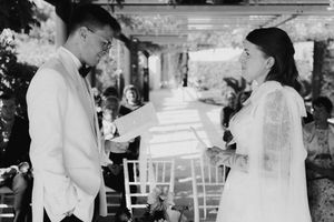 Black and white photo of a bride and groom exchanging vows at an outdoor wedding ceremony.