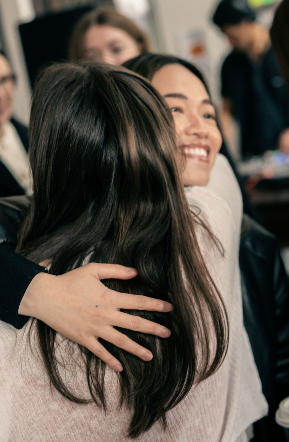 two ladies hugging at corporate event and photographer capturing it