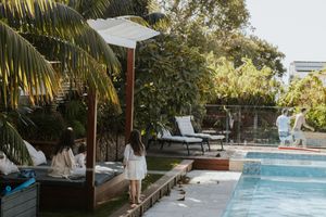 Guests relaxing by a serene outdoor pool surrounded by lush tropical greenery at a luxury resort.