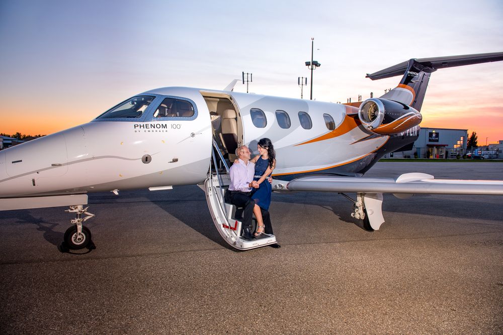 Romantic couple posing on the stairs of a Phenom private jet at sunset.