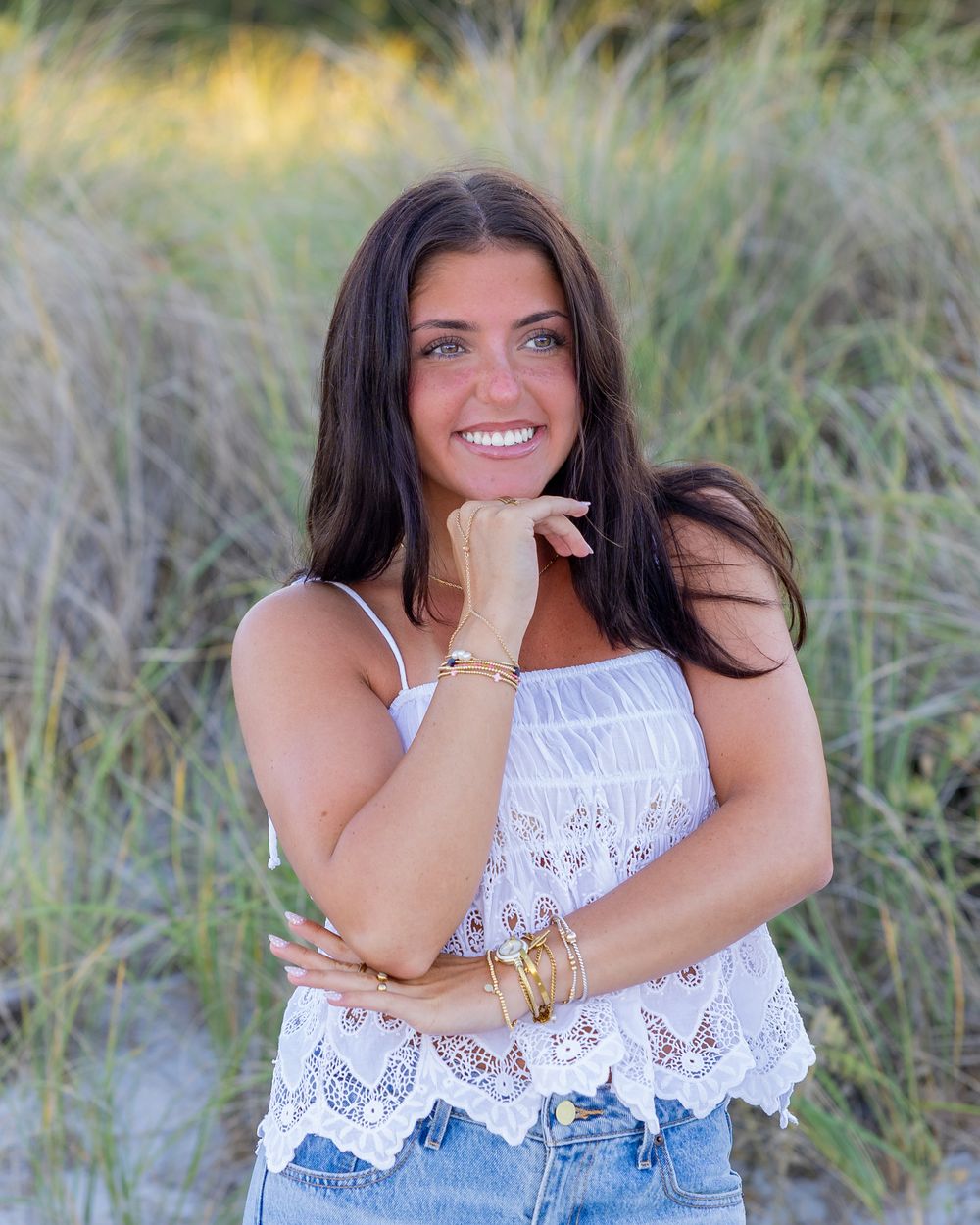 High school senior in poses in grassy dunes at Wingaersheek Beach in Gloucester, MA for yearbook portrait session at sunset golden hour.