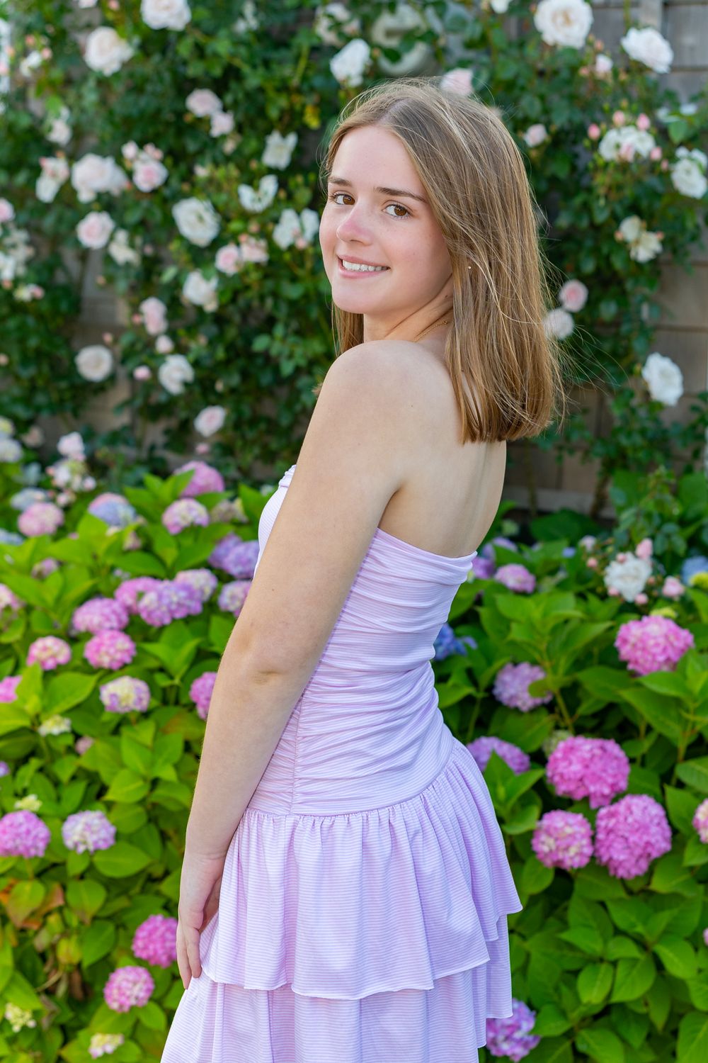 High school senior poses by climbing roses and hydrangea on Old North Wharf Nantucket, MA for her senior yearbook portrait photos.
