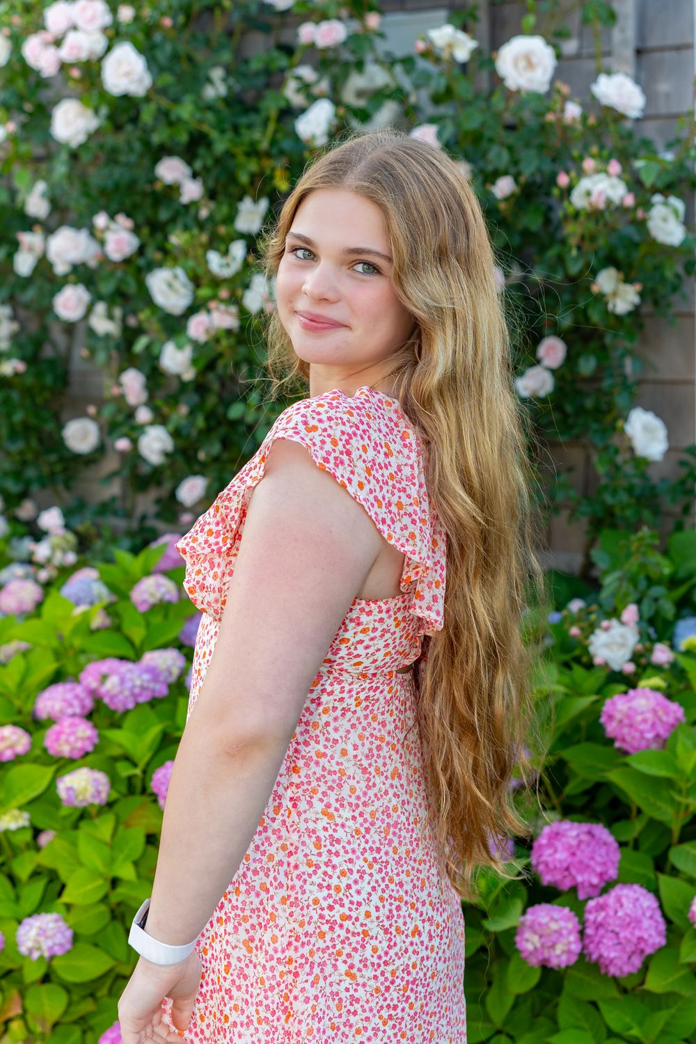 High school senior poses by climbing roses and hydrangea on Old North Wharf Nantucket, MA for her senior yearbook portrait photos.
