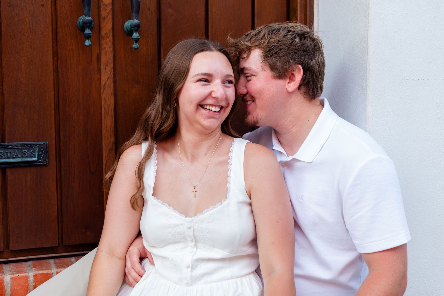 Couple laughing while seated in a doorway. Engagement photo session in Old San Juan, Puerto Rico.