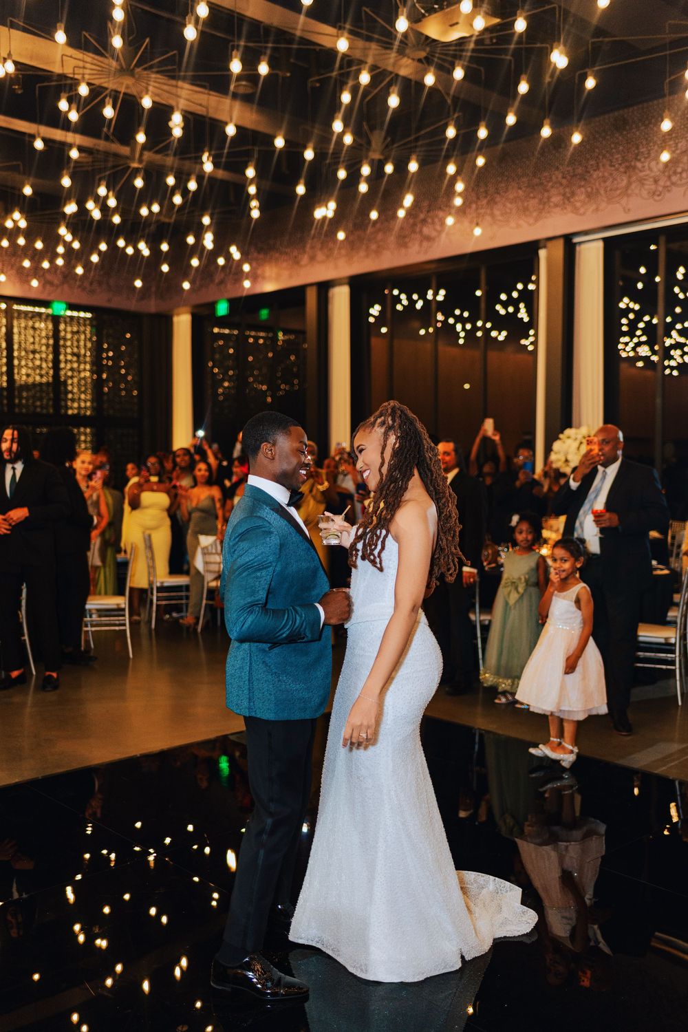 Bride and groom share their first dance under sparkling ceiling lights at an elegant wedding reception.