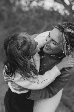 Black and white photo of two people embracing and laughing together outdoors, sharing a joyful romantic moment.