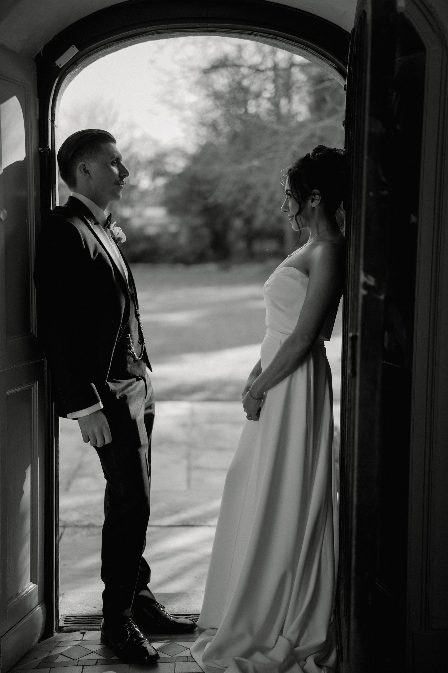 Bride and groom walk down the aisle of a gothic church with stained glass windows and candles after their wedding ceremony.