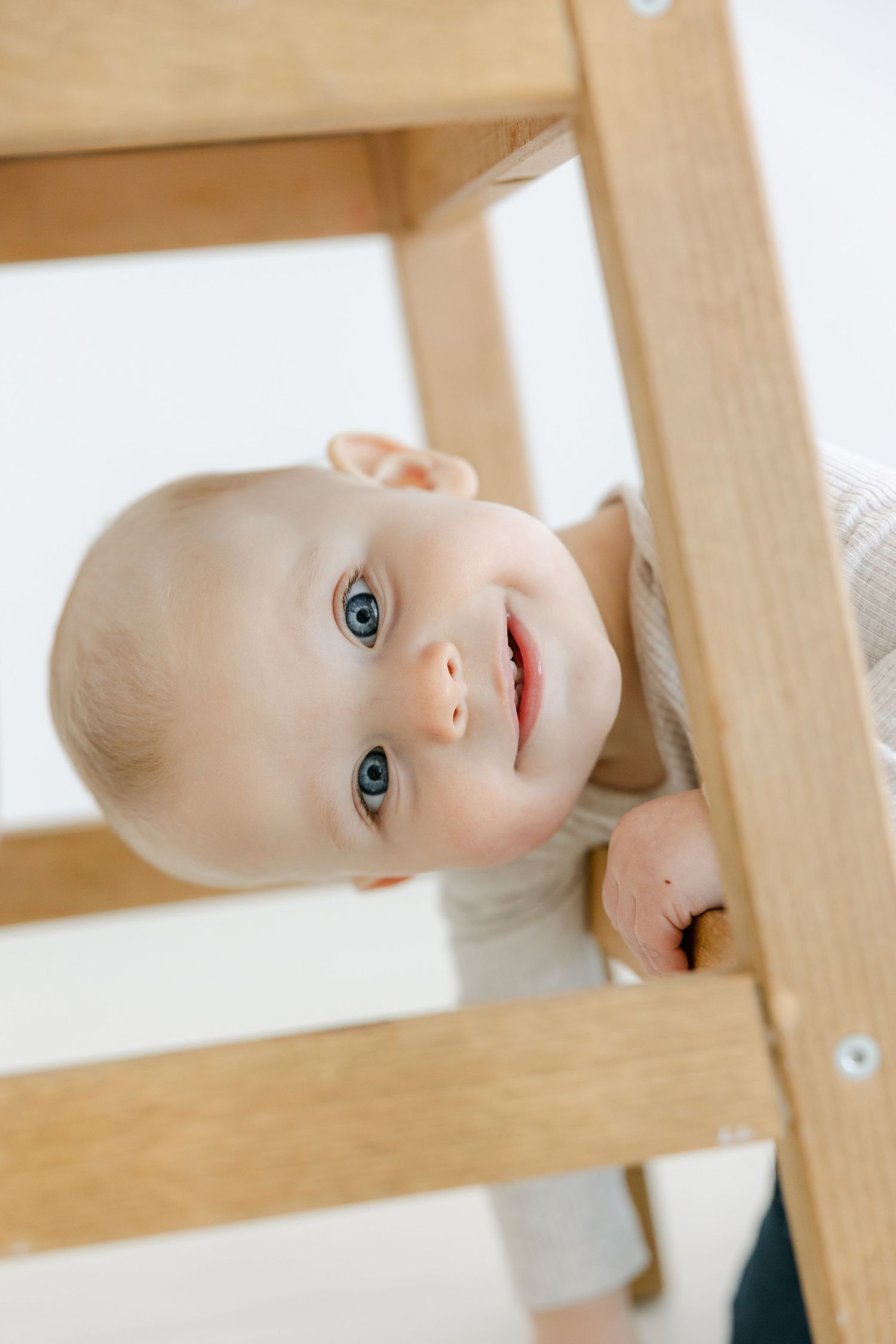 Close-up of a baby's head with a tiny hair curl and a white lace bow headband.