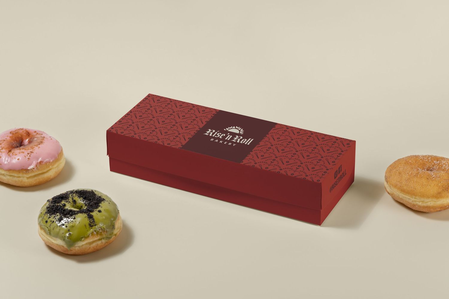 Red Rise n Roll Bakery rectangular box with assorted frosted donuts on beige background.
