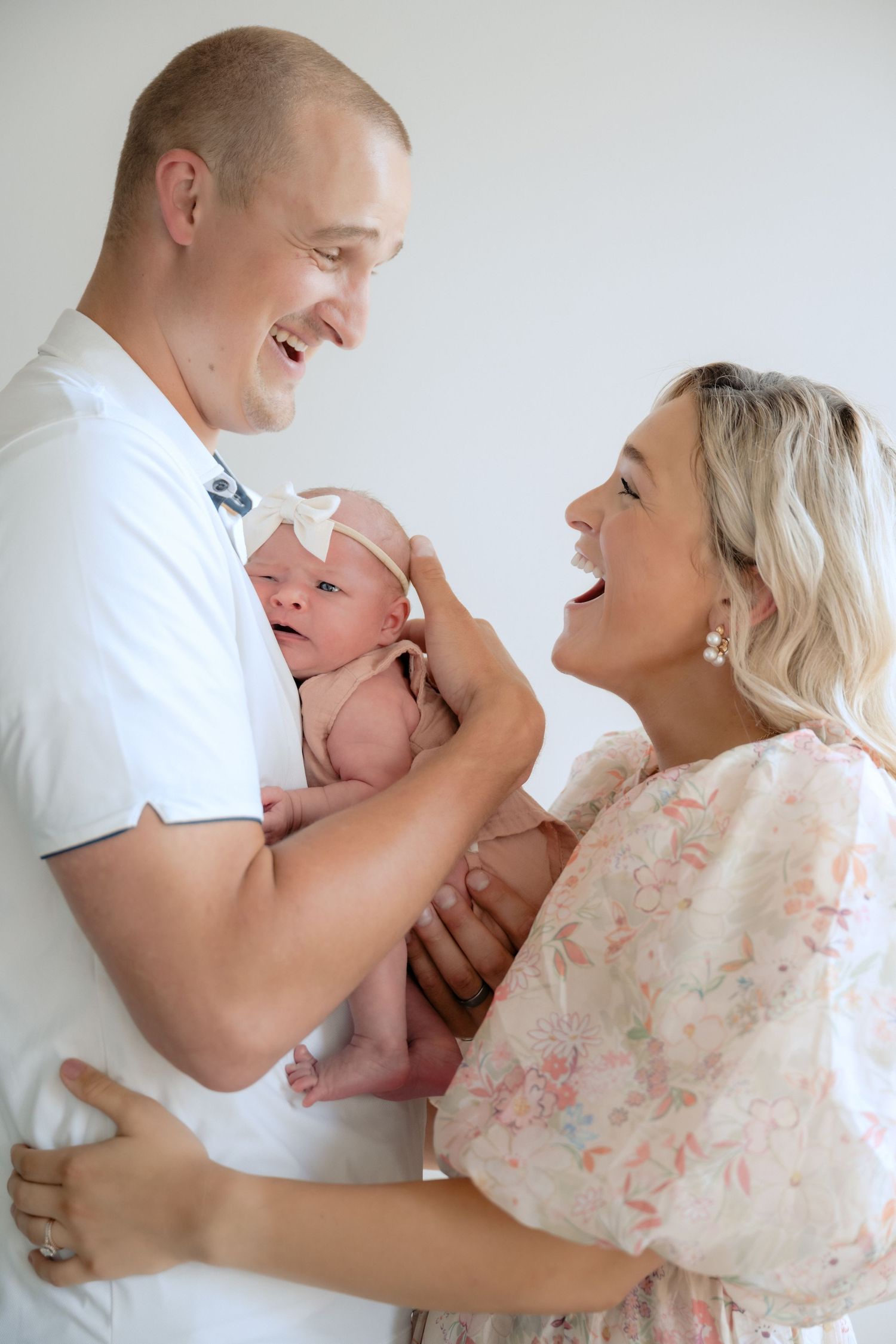 parents laughing at each other while holding newborn baby during in-studio lifestyle newborn portraits in stillwater, mn