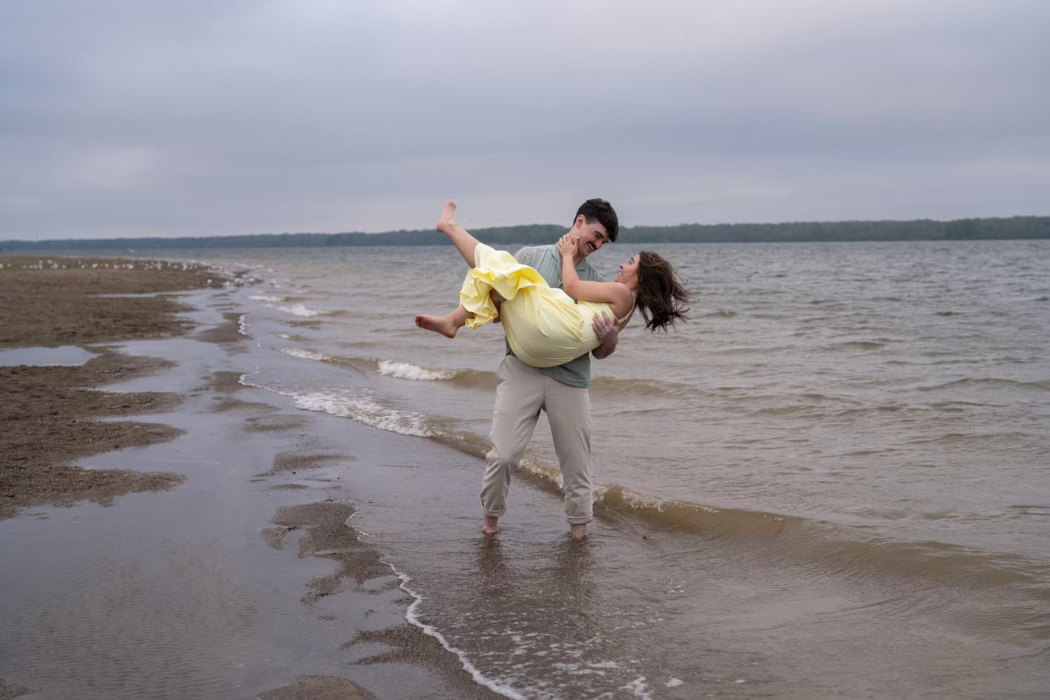 Couple playing on a sandy beach shore at Alum Creek Beach Engagement Photos