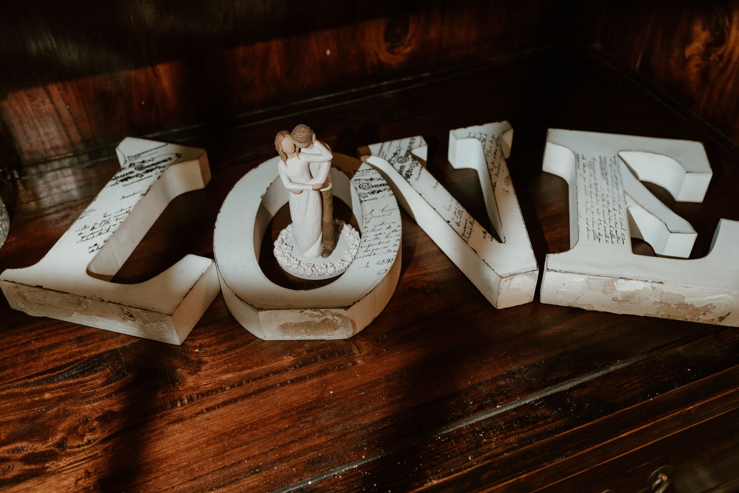 Crystal-embellished bridal heels beside a bottle of 909 eau de parfum and pearl drop earrings on a wooden surface.