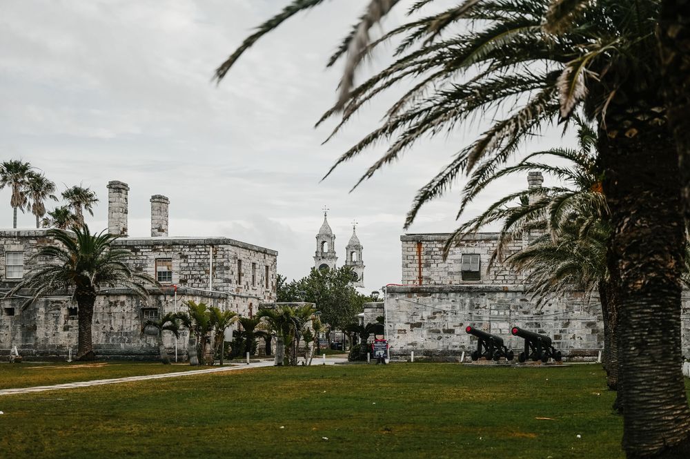 Historic stone fort with cannons, palm trees, and church towers under cloudy skies in St. Augustine, Florida.