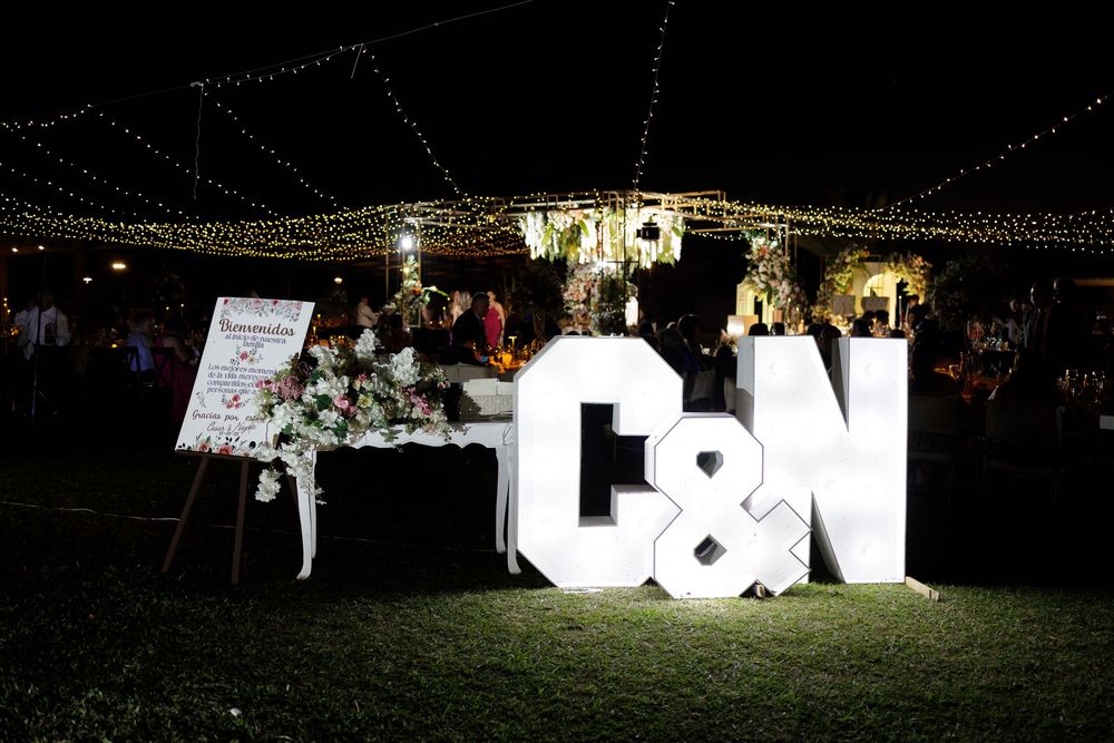 Illuminated C&N wedding monogram letters displayed outdoors at night with fairy lights and floral arrangements.