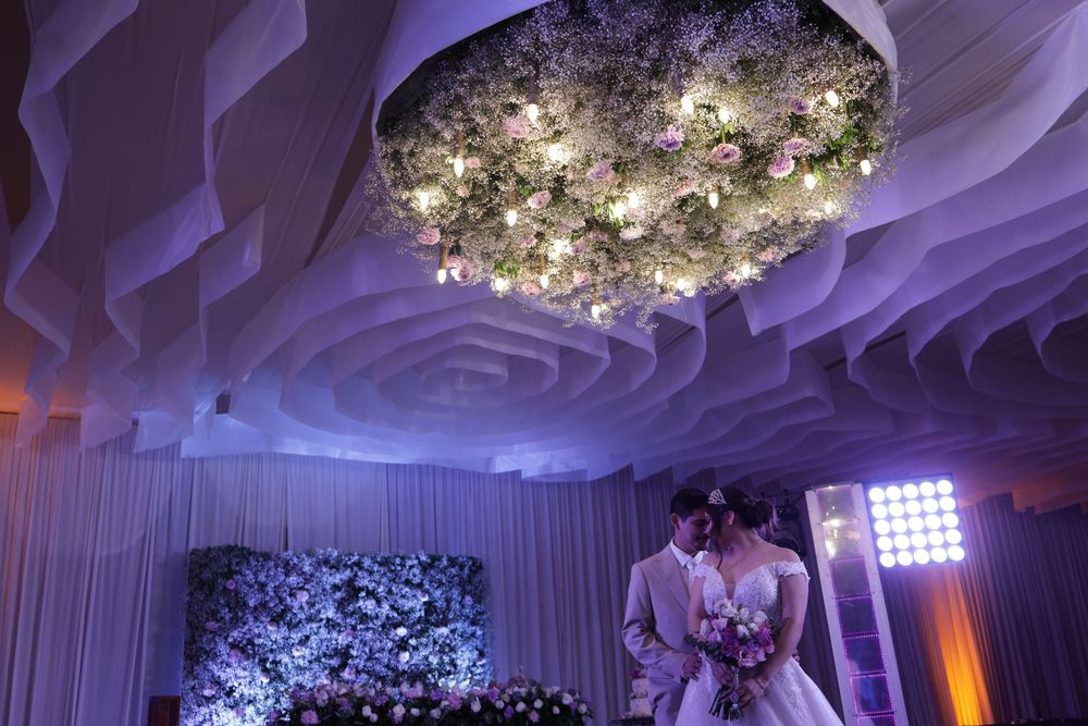 Bride and groom share a romantic moment under an elegant floral chandelier at a beautifully decorated wedding reception.