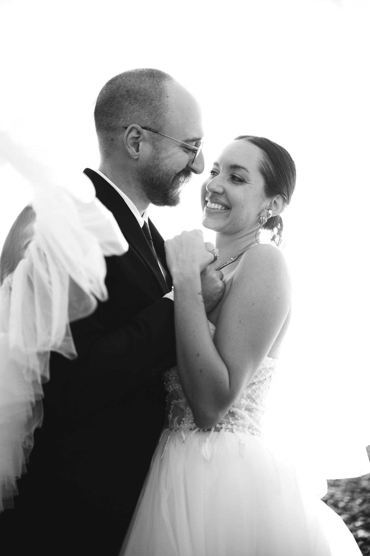 Black and white photo of a smiling bride and groom sharing a tender moment during their first dance at their wedding.