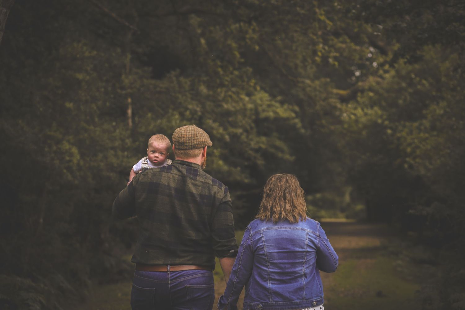 Family walking together on wooded path during autumn.
