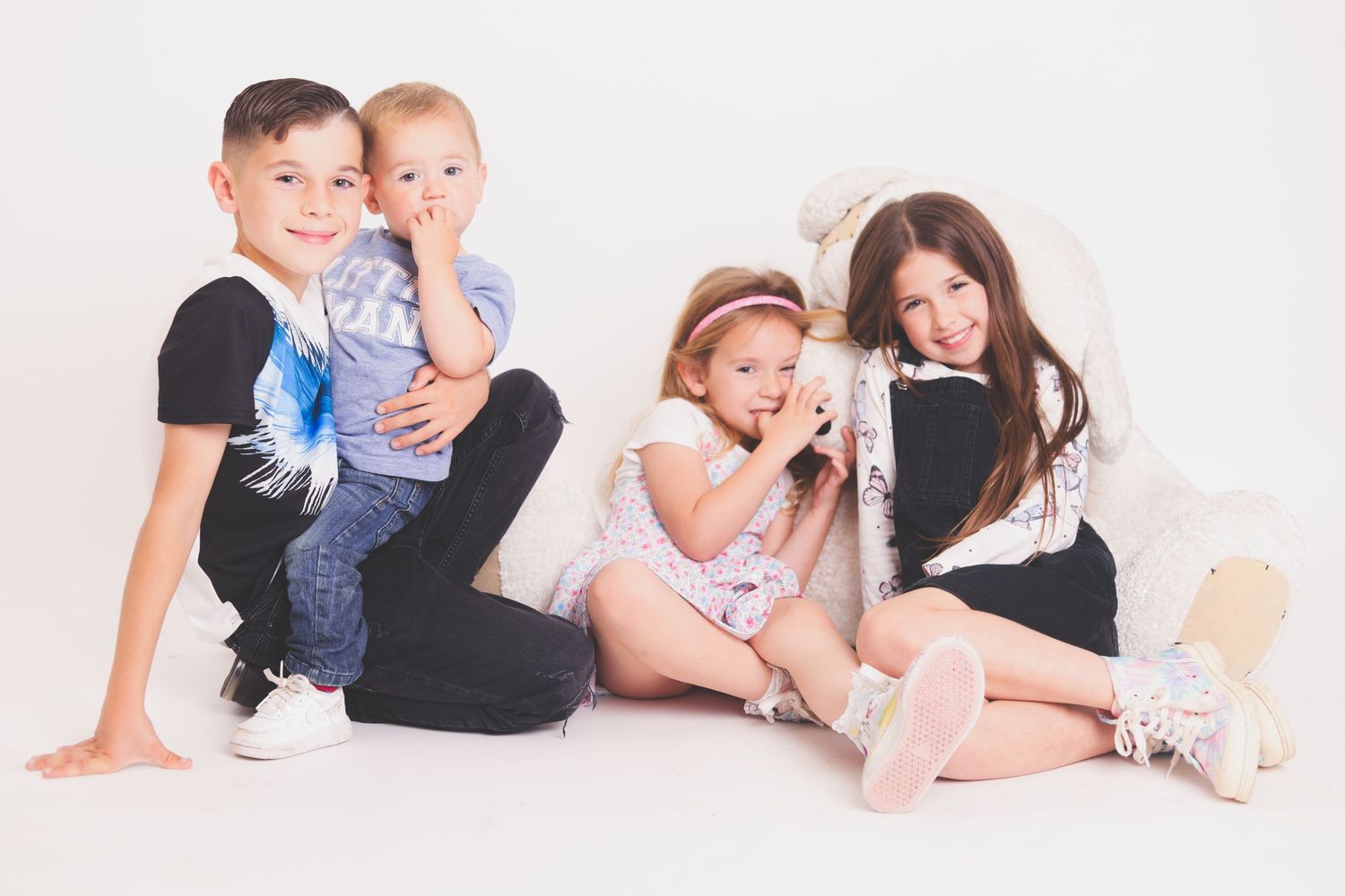 Group of children posed together on white studio background.