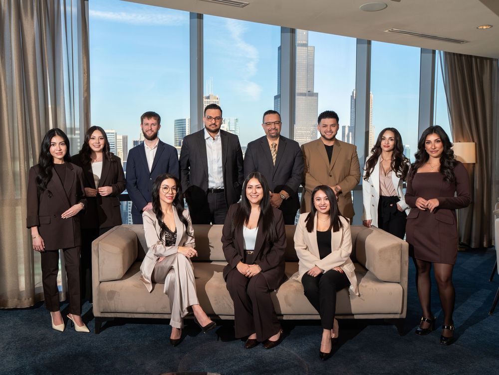 Professional corporate team of eleven colleagues posing in a modern high-rise office with city skyline views.