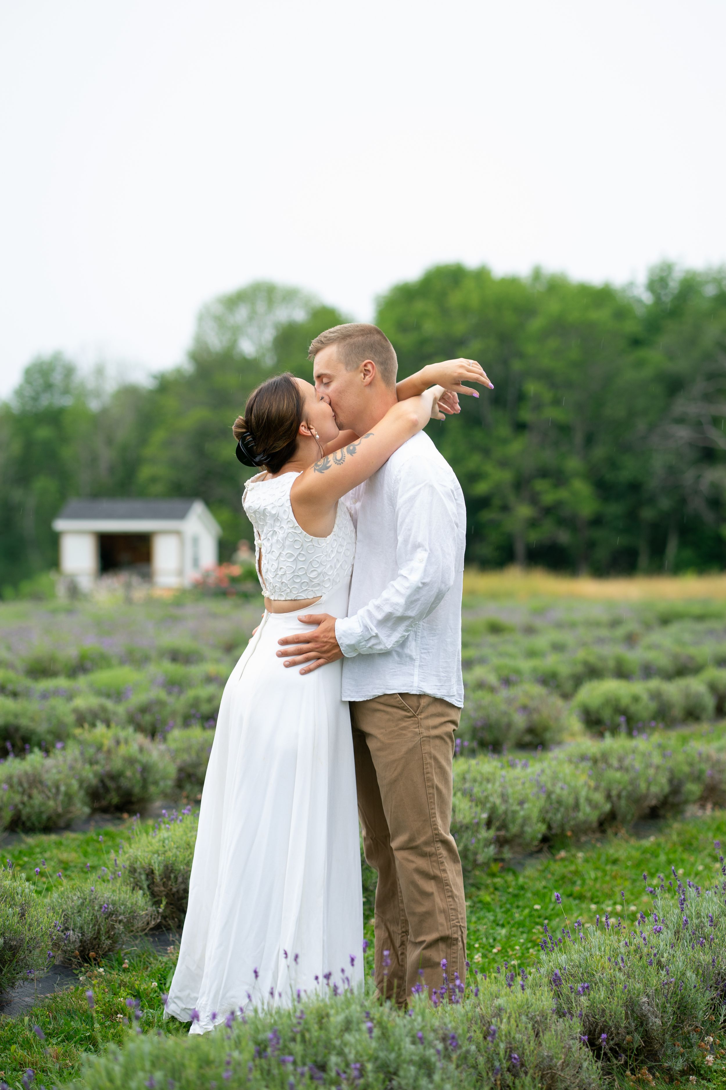 A couple shares a sweet kiss while embracing in a blooming lavender field during their engagement session.