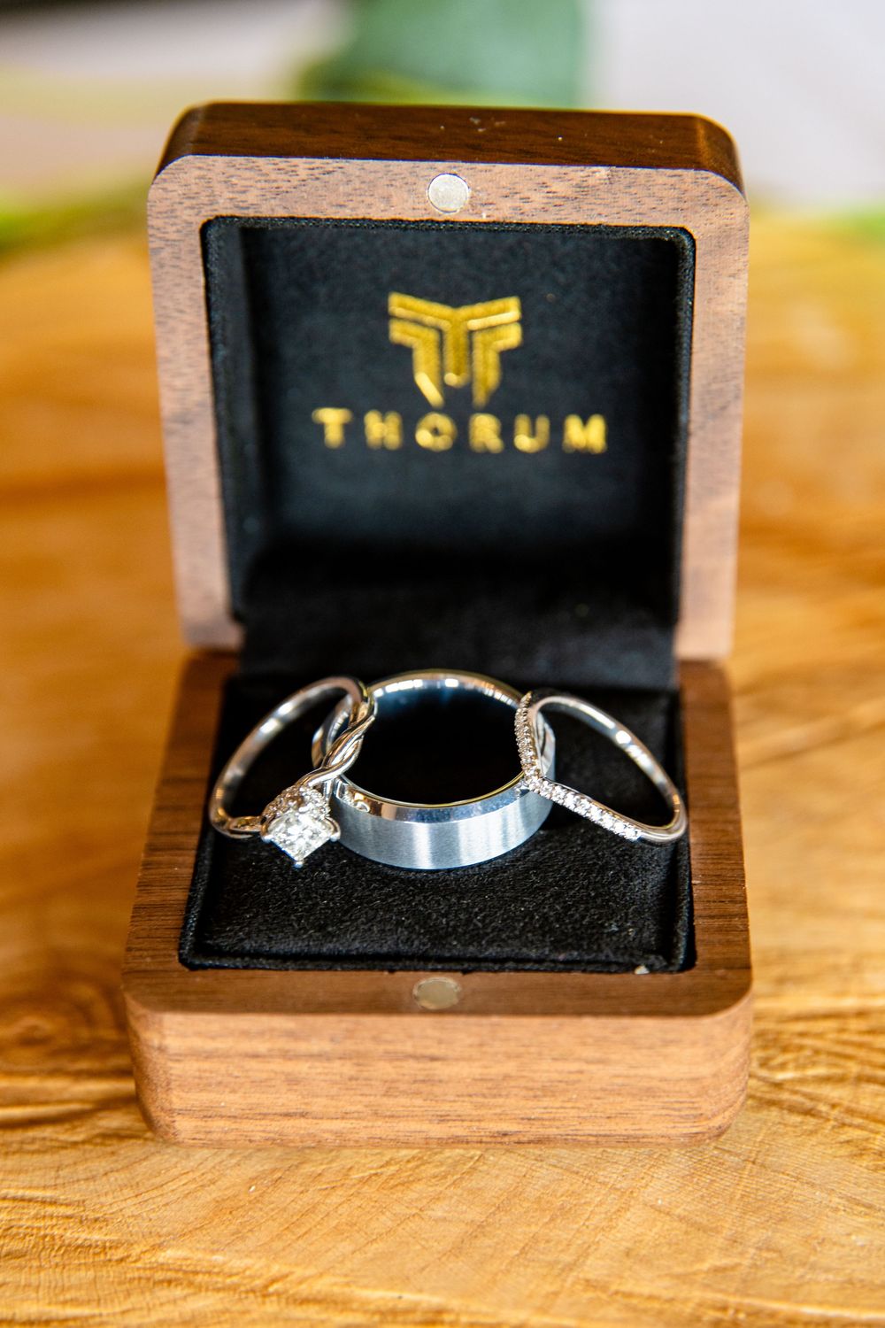 Three wedding rings displayed in a wooden Thorum ring box with black velvet interior.
