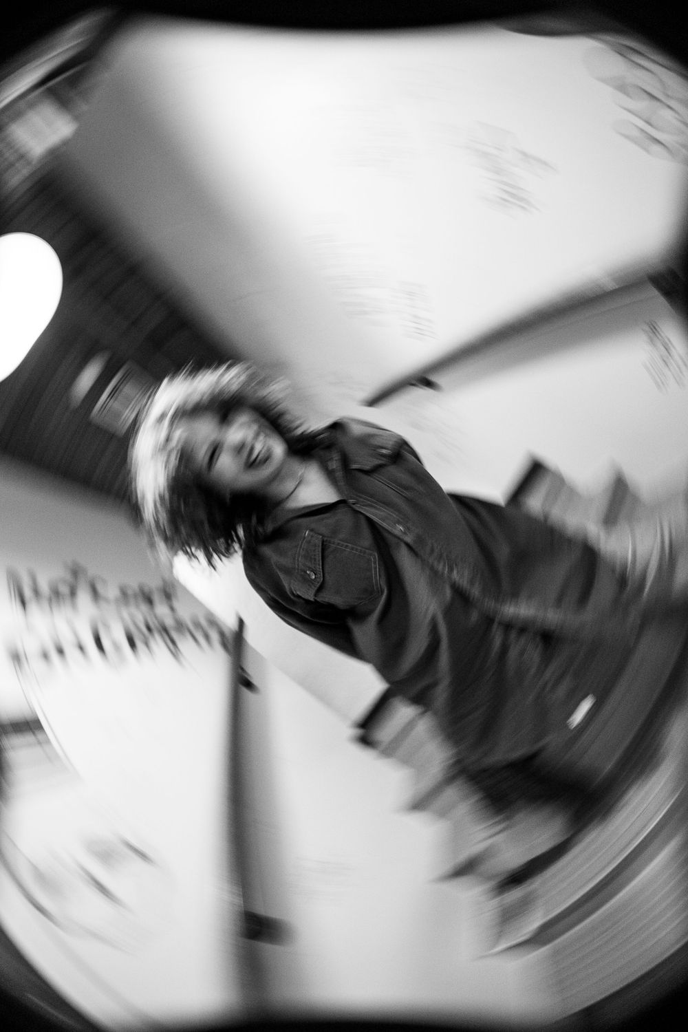 Black and white motion blur photo of a person spinning, captured with a fisheye lens effect.