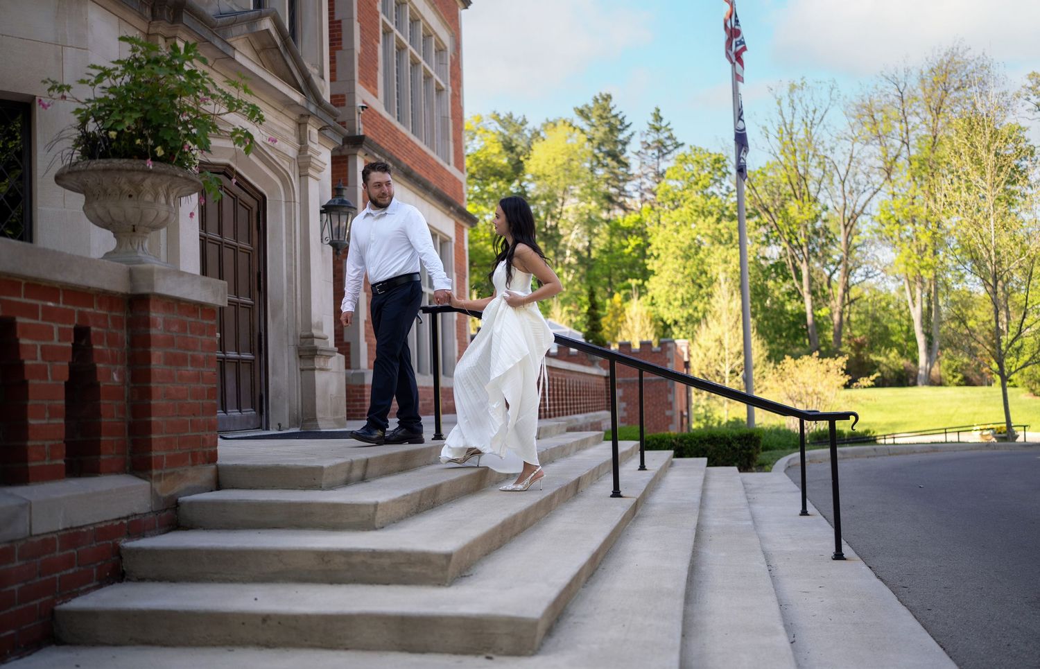 Couple in formal attire descending stone steps of Jeffrey Mansion for their Engagement Session