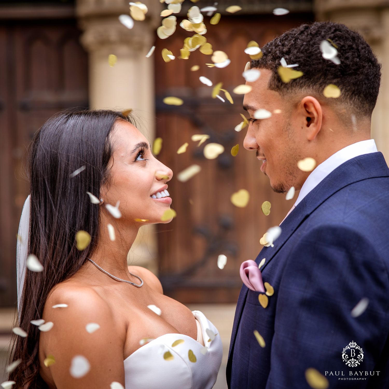 Black and white photo of a smiling bride and groom exchanging vows at an elegant wedding ceremony.
