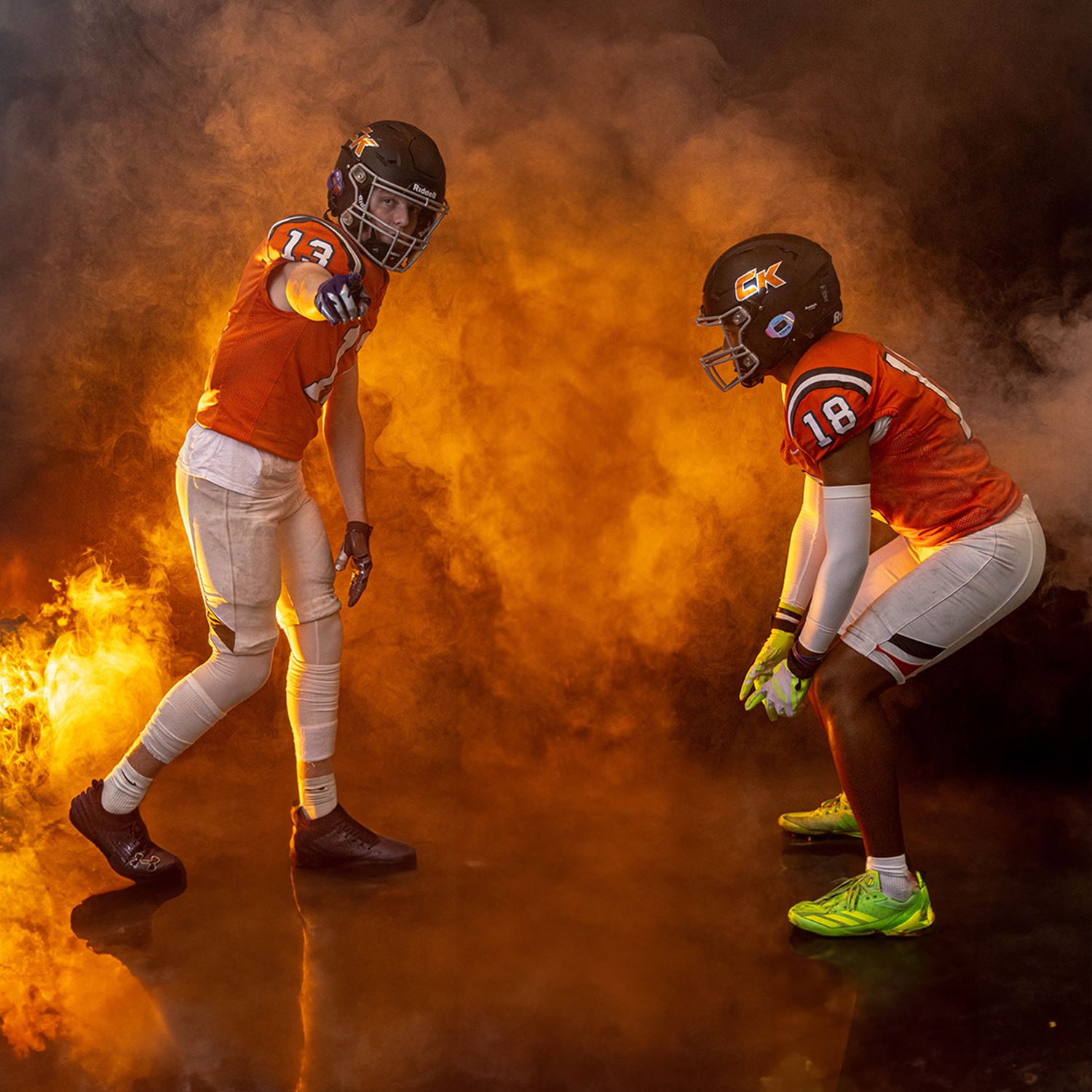 Two football players facing off with dramatic orange smoke effect in background.