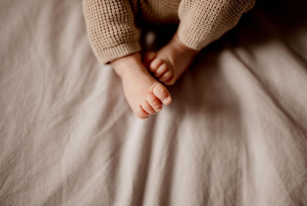 Gros plan de petits pieds de bébé sur un tissu en tricot beige doux.