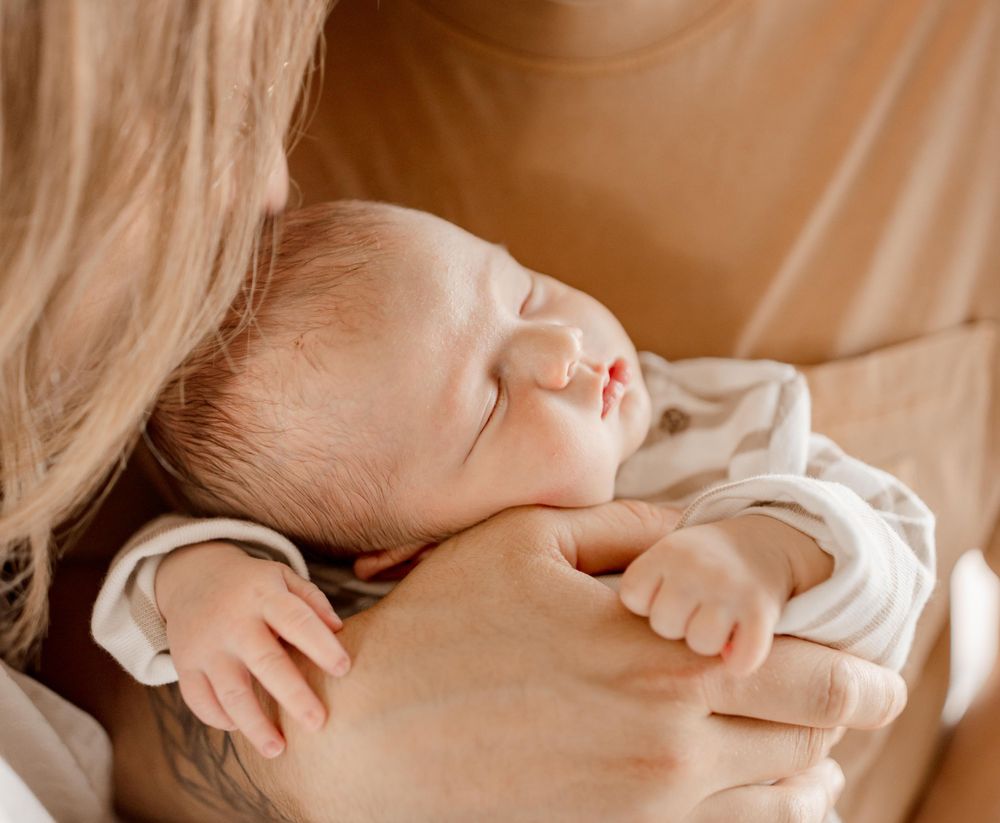 Bébé endormi paisiblement dans des vêtements blancs blotti contre un tissu doux.