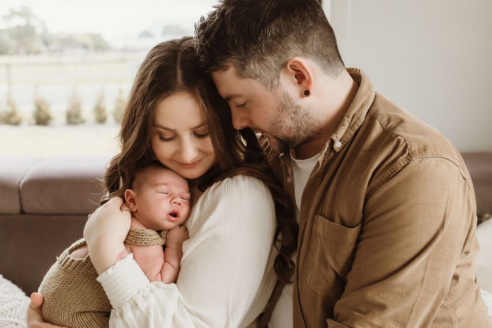New parents tenderly holding their sleeping newborn baby together in a warm, intimate home setting.