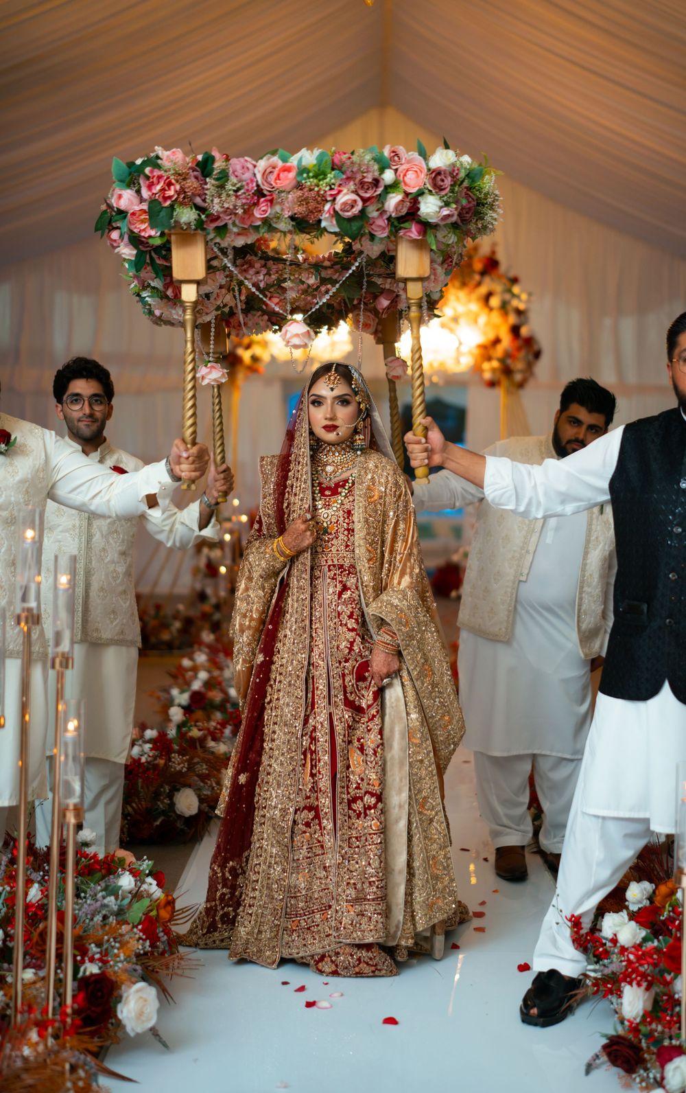 Wedding ceremony decor features a floral archway with pink roses and elegant white lanterns in the background.