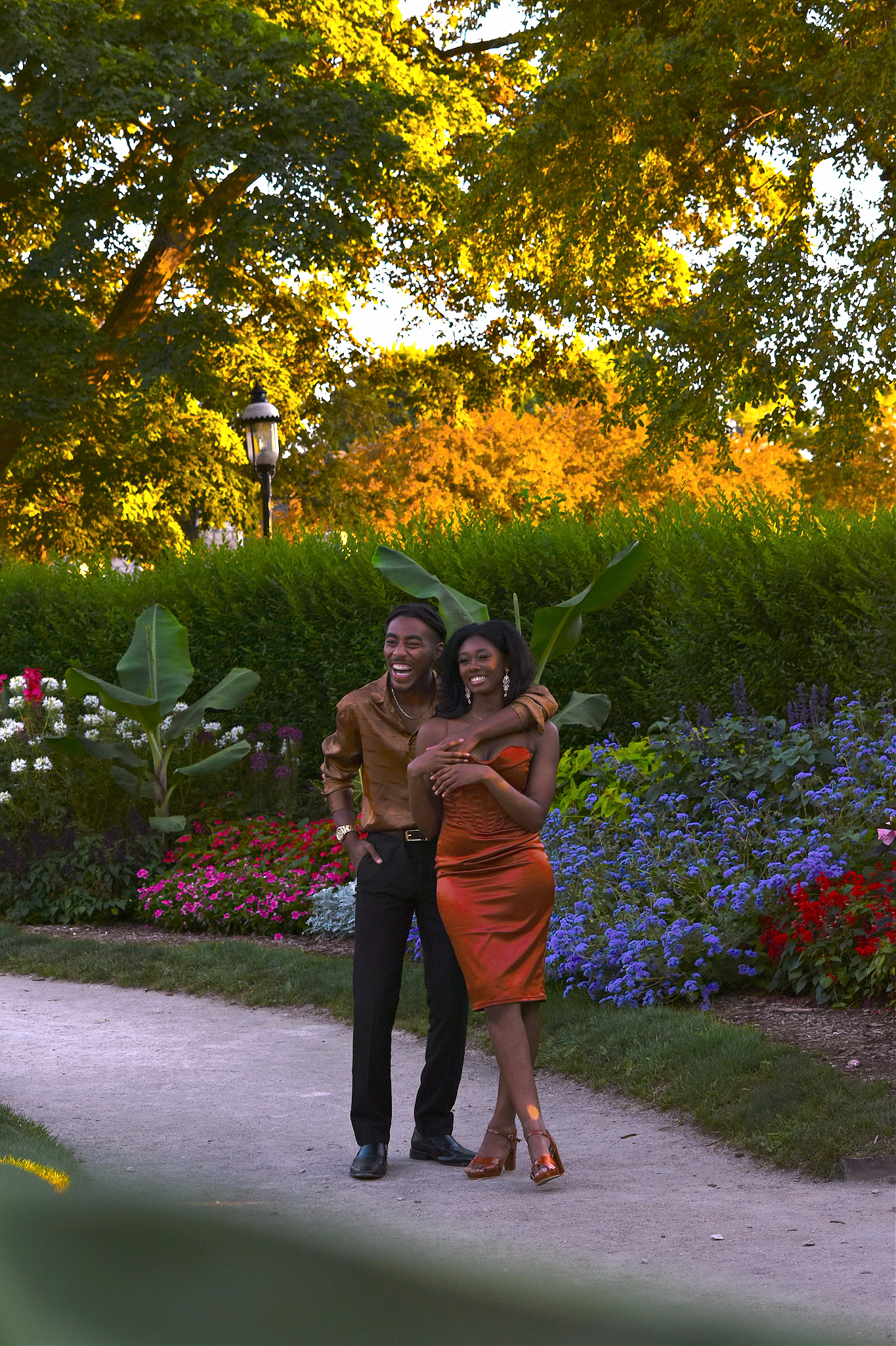 A joyful couple laughing together on a garden path during golden hour.