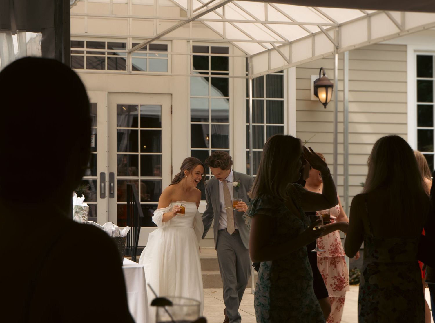 Wedding celebration inside a white tent structure with guests gathering around the newlyweds.