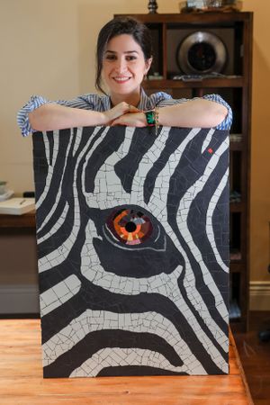 Artist displays striking black and white zebra-inspired mosaic artwork featuring an orange eye design at center.
