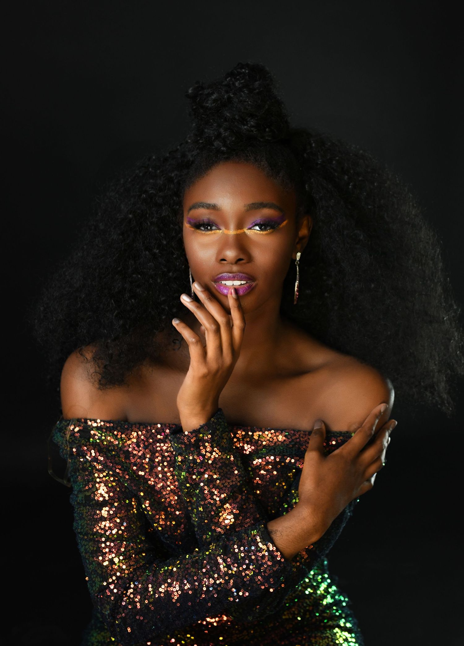 A stunning portrait of someone wearing a sparkly off-shoulder dress against a dark background.