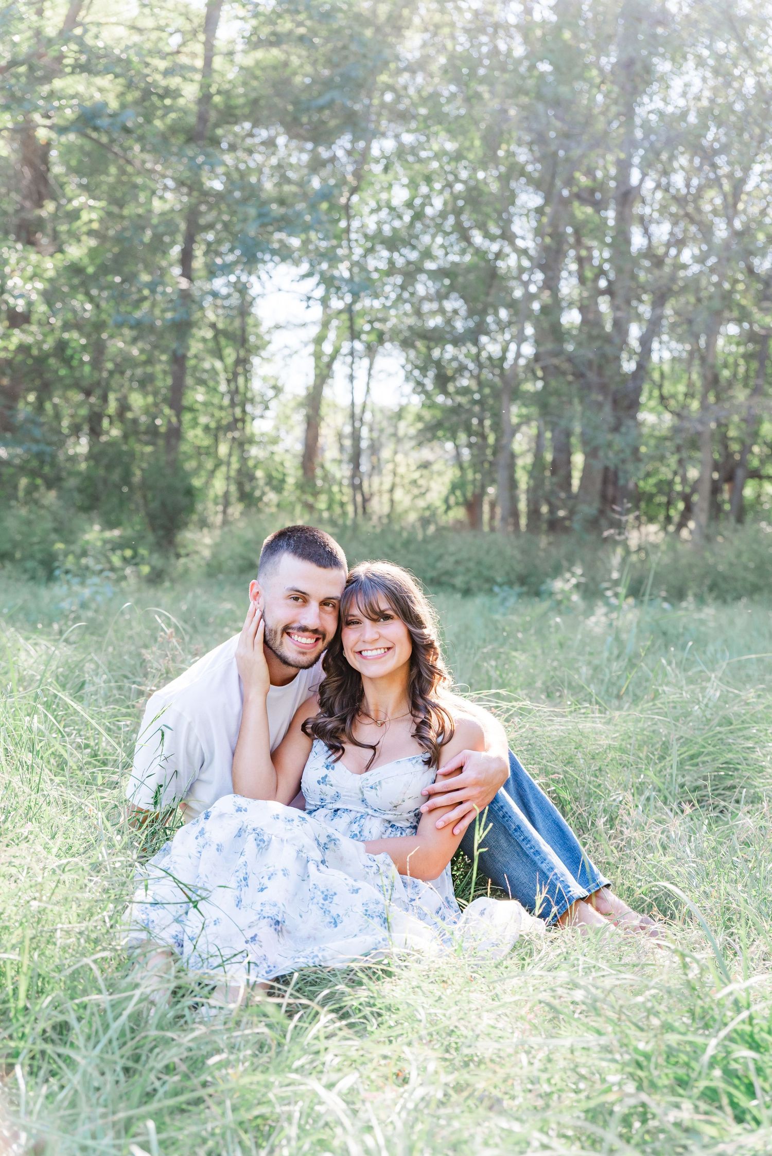 A couple's engagement portraits sitting in a field in Kuttawa, KY.