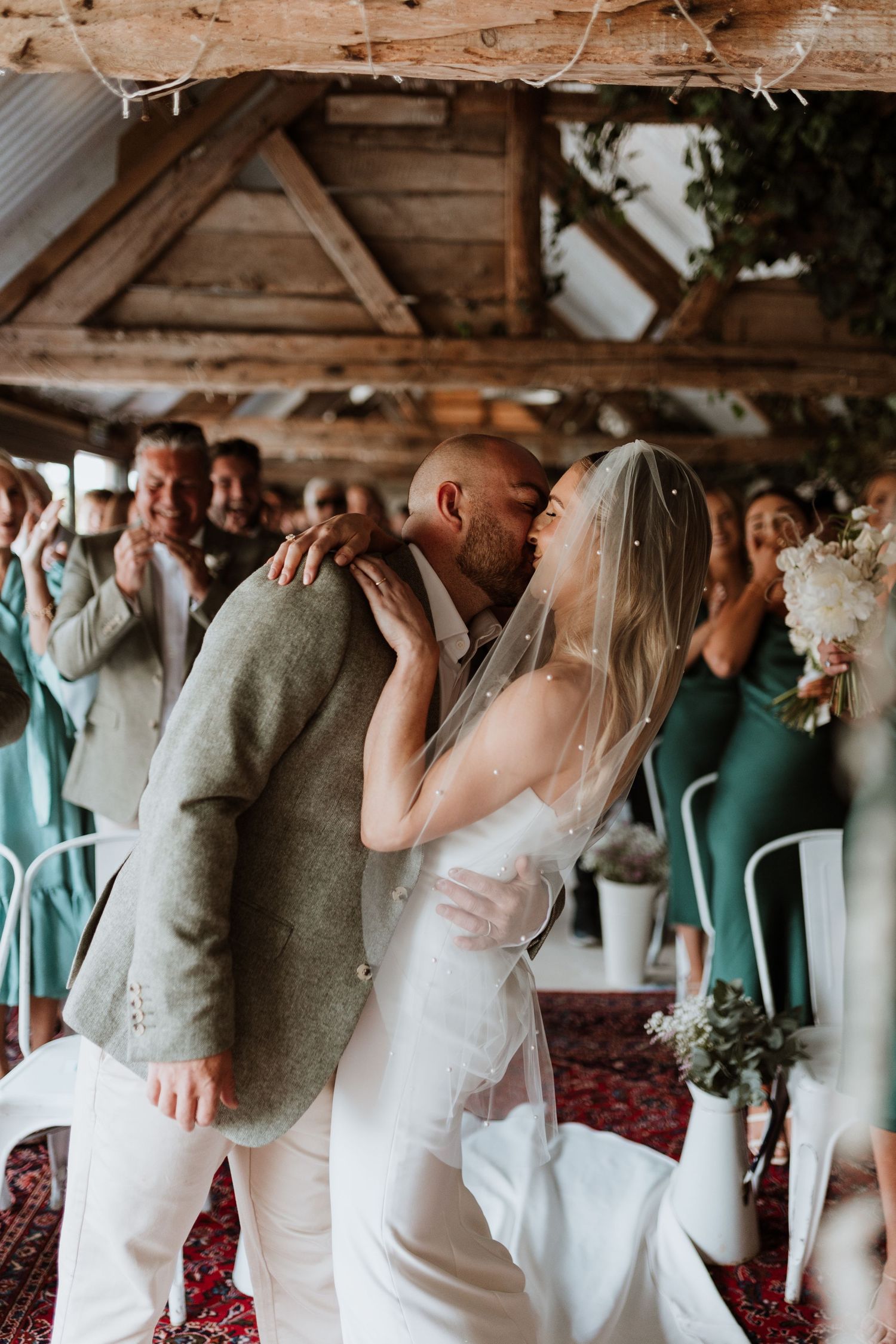 A newlywed couple share first kiss in the long barn at Wilde Lodge