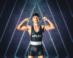 Athletic person in workout attire flexing muscles against dark background with dramatic lighting.
