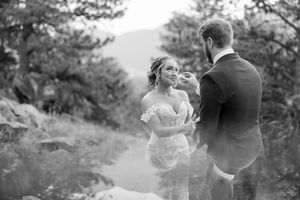 A romantic black and white wedding photo shows a couple sharing an intimate moment on a wooded path.