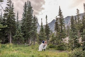 Wedding couple poses in scenic mountain landscape surrounded by evergreen trees.