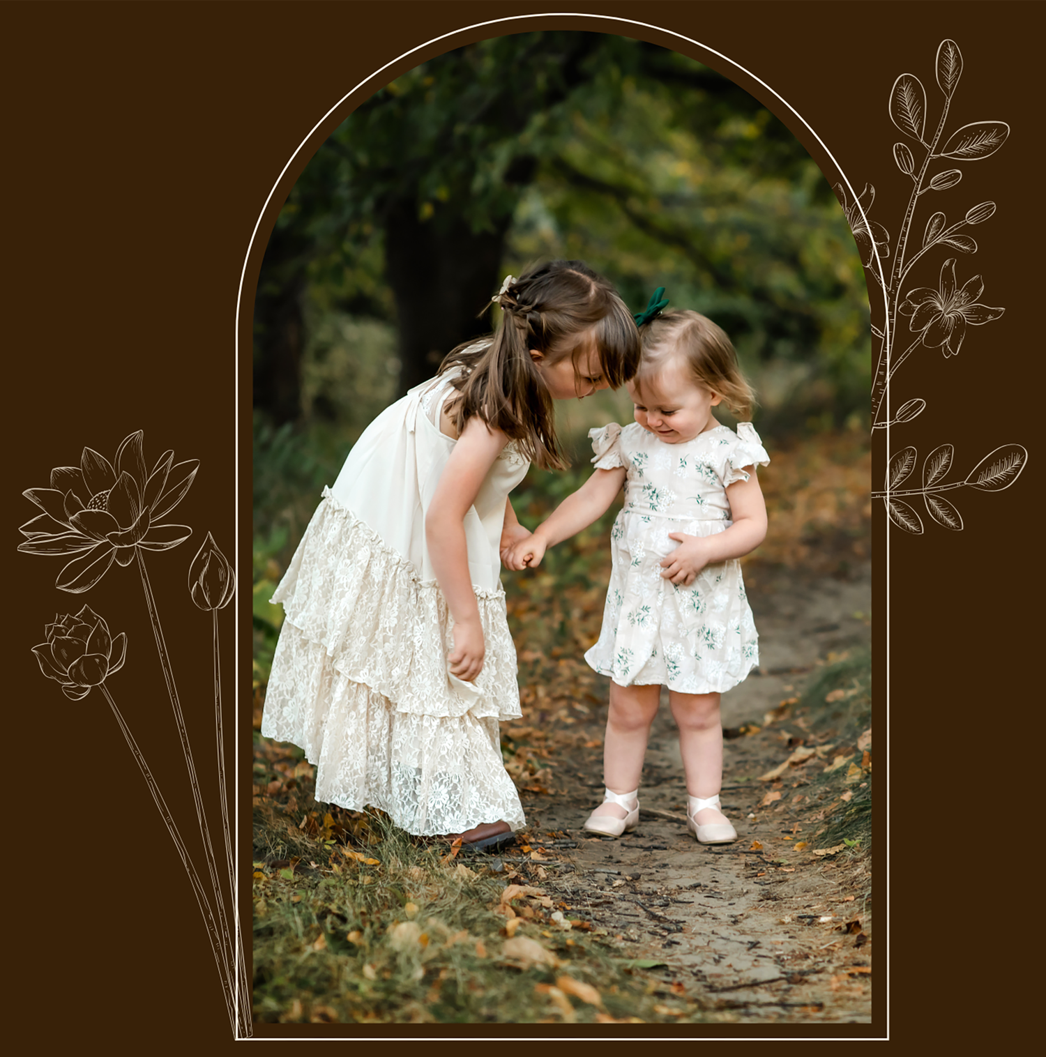 Two children in white dresses share a sweet moment together on a woodland path framed by an arched border with floral designs.