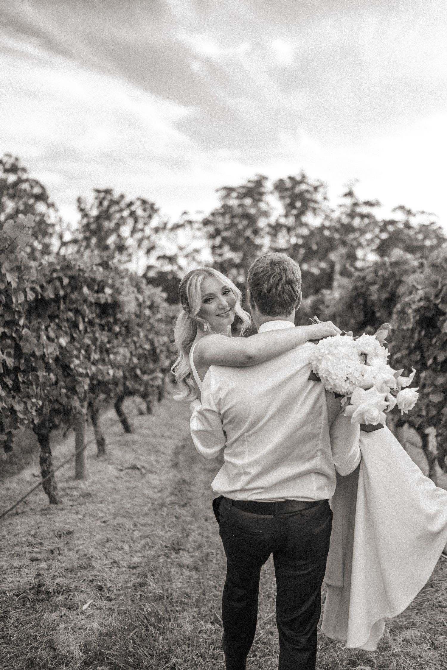 Outdoor wedding ceremony with floral arch and chandelier in vineyard setting