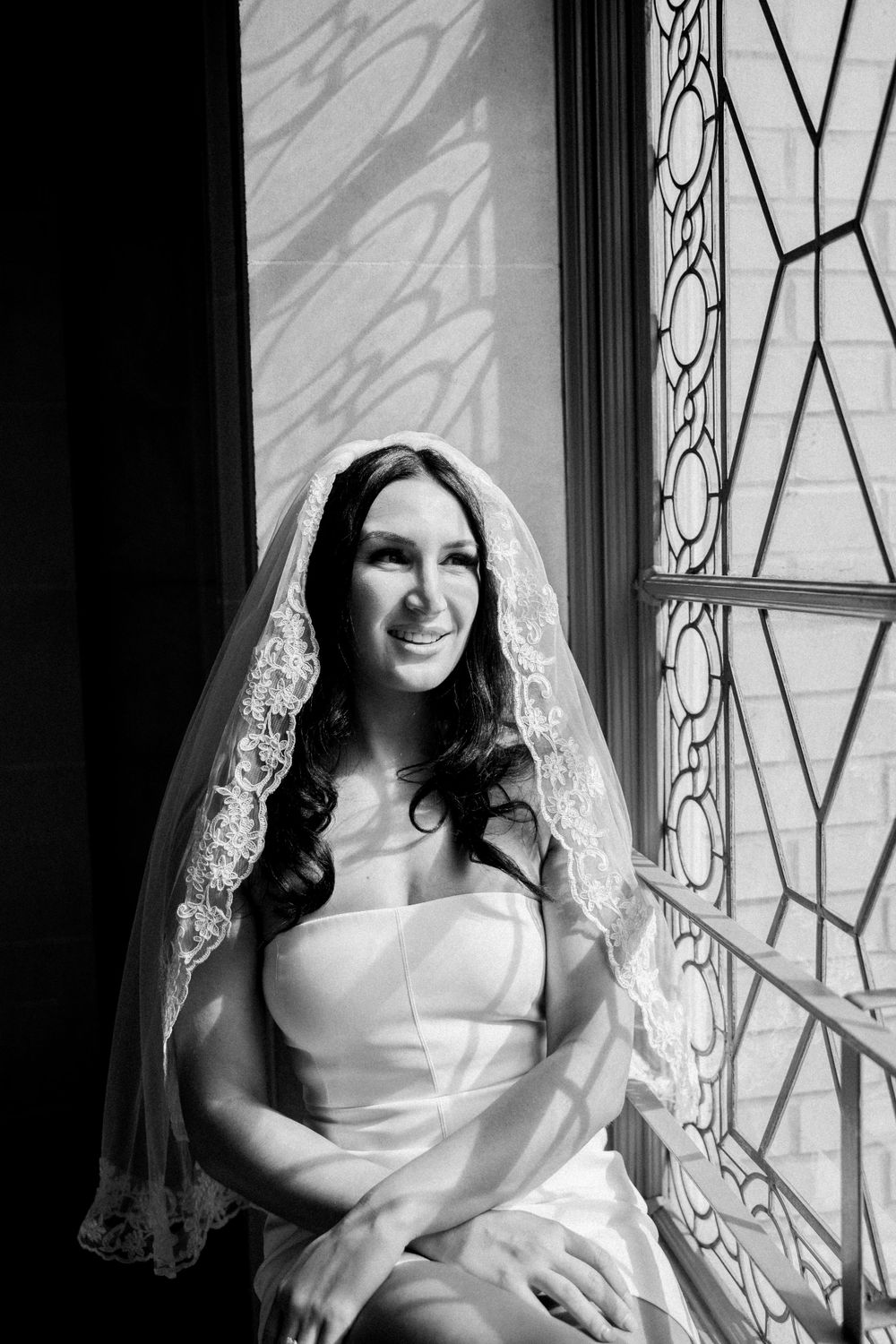 White bride sits in beautiful ornate windowsill before eloping at San Francisco City Hall.,