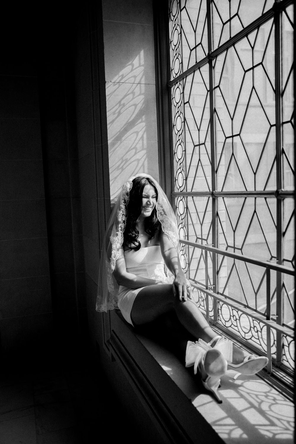 White bride sits in beautiful ornate windowsill before eloping at San Francisco City Hall.,