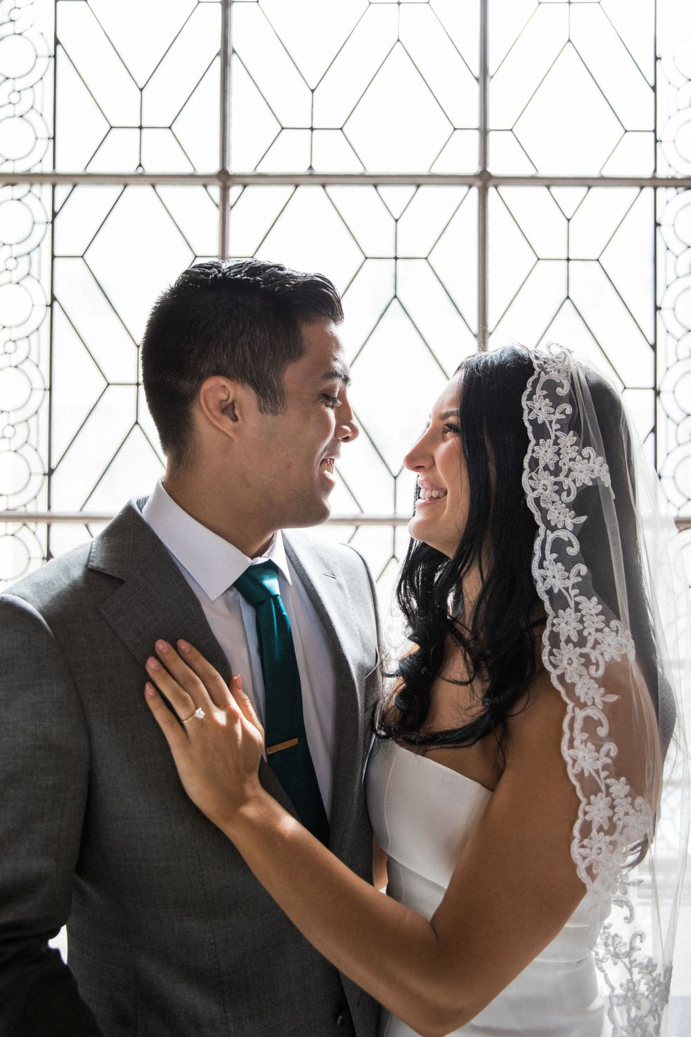 Asian groom and Caucasian bride in short wedding dress smile after getting married at San Francisco City Hall.