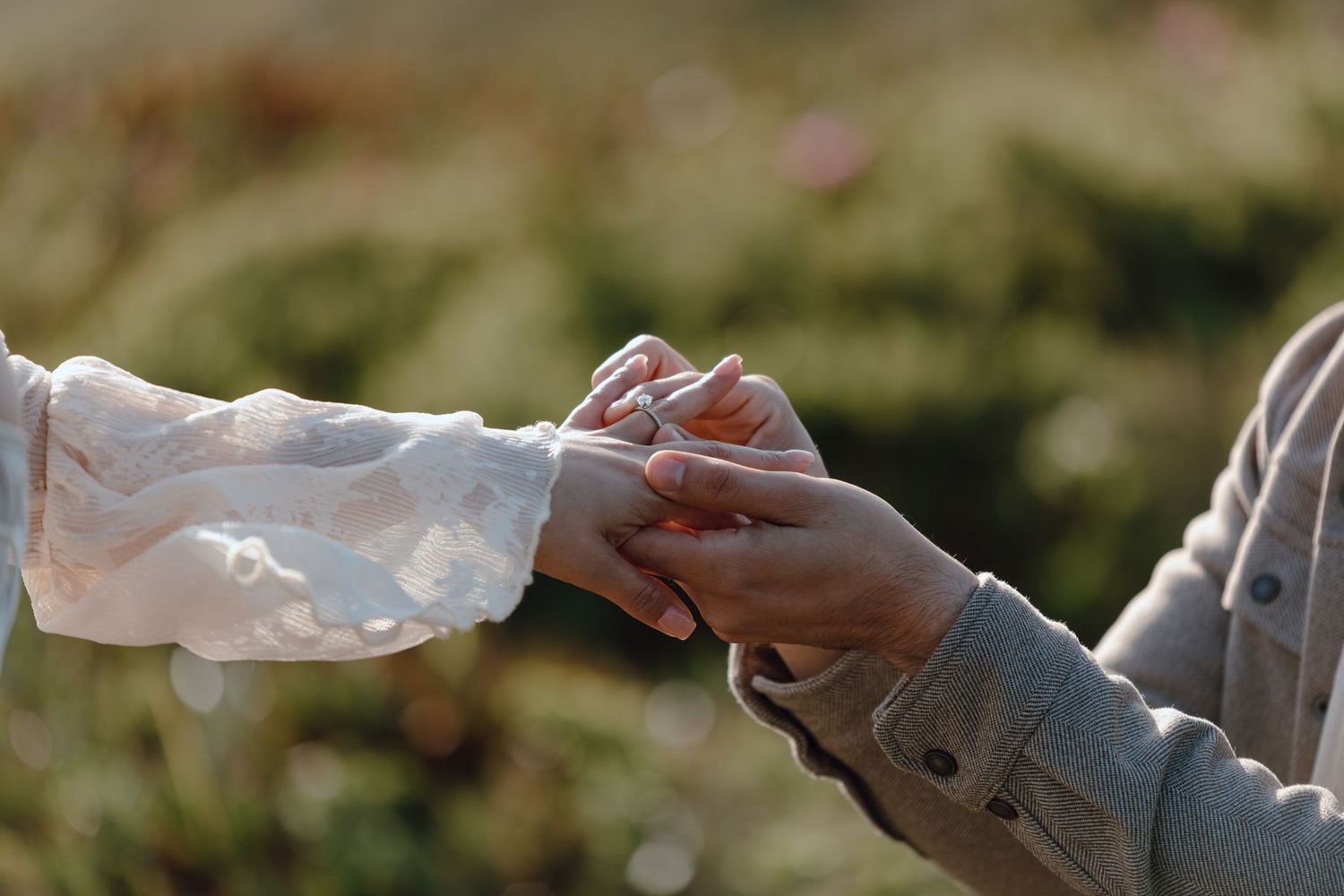 Close-up of hands exchanging rings during an intimate outdoor ceremony.